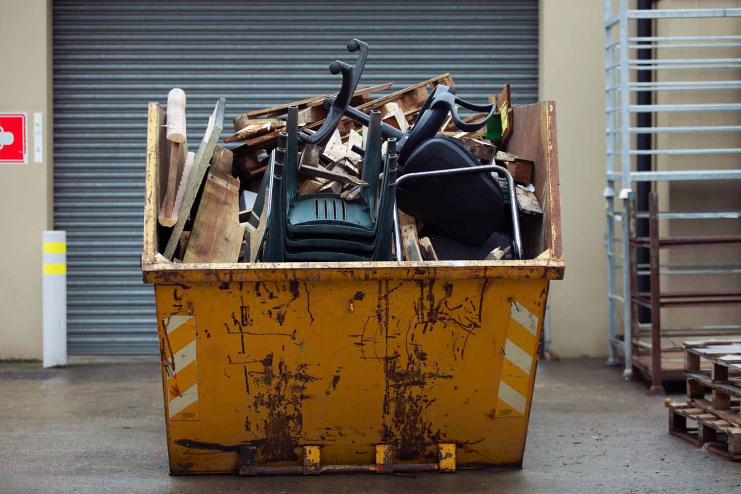 Garbage dumpster full of office furniture